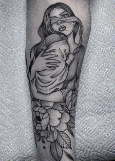 a black and white tattoo on the leg of a woman holding a baby in her arms