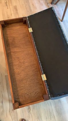 an empty wooden box sitting on top of a hard wood floor next to a pair of shoes