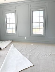 an empty room with white carpet and three windows