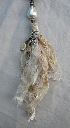 a necklace with beads and lace on it sitting on top of a piece of cloth