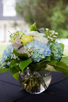 a vase filled with blue and white flowers on top of a black cloth covered table