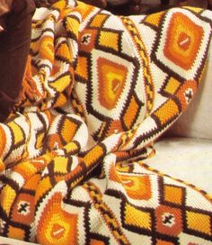 a woman laying on top of a couch under a blanket next to a pillow and coffee cup