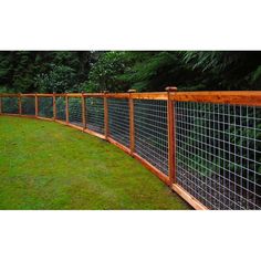 a wooden fence with wire on top and green grass in the backgroung