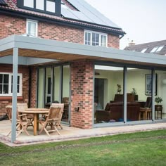 a patio with an awning over it and wooden furniture on the ground next to brick building