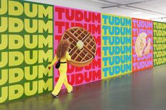 a woman in yellow is walking past a wall with large letters on it and an image of a giant waffle