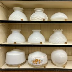 several white vases and bowls are on shelves