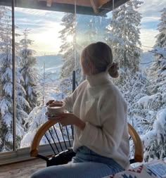 a woman sitting at a table with a cup of coffee in front of a window