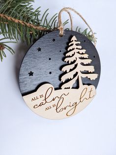 a wooden ornament hanging from a christmas tree with the words, all is calm and bright