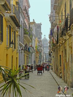 an old city street with people walking down it