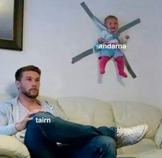 a man sitting on top of a white couch next to a baby in a blue shirt