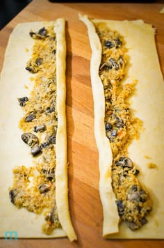 two uncooked pizzas sitting on top of a wooden cutting board