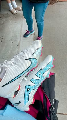 a pair of nike shoes sitting on top of a pile of clothes next to a woman