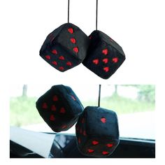 two black dices with red hearts are hanging from the car's dash board