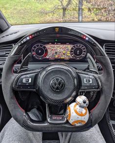 the interior of a car with steering wheel and star wars character stuffed animal in it