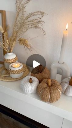 a white mantle with pumpkins and candles on it