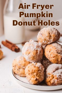 a pile of doughnut holes sitting on top of a plate next to a glass of milk