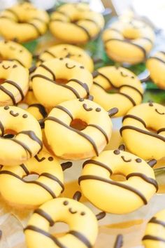 there are many yellow donuts with chocolate stripes on them and smiling faces in the middle