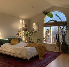 a bedroom with a large bed and lots of plants in the window sill area