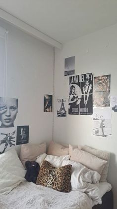 an unmade bed in a small room with posters on the wall and pictures above it