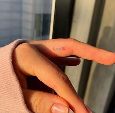 a woman's hand with the word love written on it, in front of a window