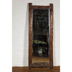 a large mirror sitting on top of a wooden floor next to a white brick wall