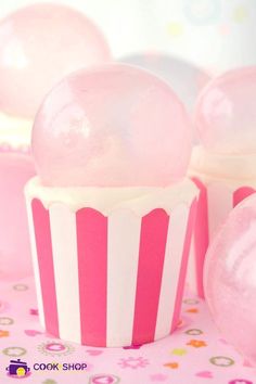 pink and white cupcakes with frosting on them sitting on a tablecloth