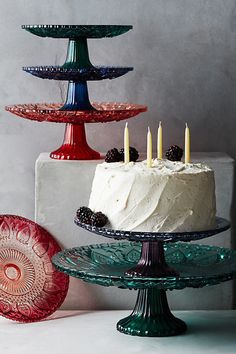 three tiered cake stands with white frosting and blackberries on top, one is red