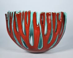 a red and blue vase with wavy lines on it's sides, against a white background