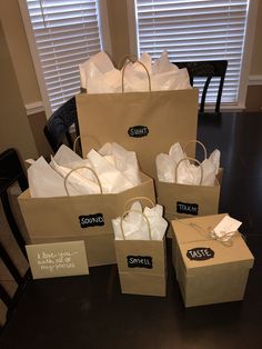 several brown paper bags with tags on them are sitting on a table in front of two windows