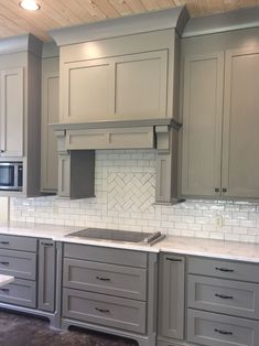 a kitchen with gray cabinets and white tile backsplashes on the countertops