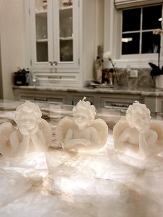 three little buddha figurines sitting on top of a marble counter in a kitchen