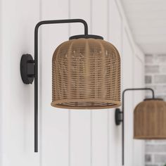 two wicker lamps hanging from the side of a white wall next to a door