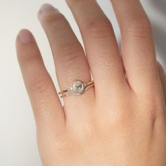 a woman's hand with a diamond ring on top of her finger and an engagement band