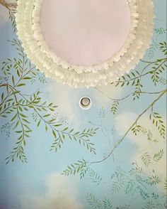 the ceiling is painted with blue and green leaves on it, as well as a white doily