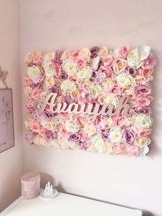 a pink and white flower wall in a girls's room with the name aurora written on it