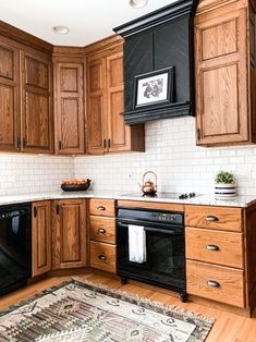 a kitchen with wooden cabinets and black appliances in it's center island, along with a rug on the floor