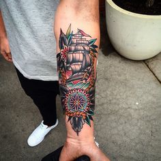 a man's arm with a ship tattoo on it