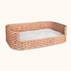 a dog bed made out of wicker with a white pillow in the bottom corner