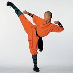 a man in an orange outfit is doing a kickbox pose with one leg on the ground