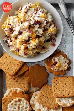 crackers are arranged on a tray next to a bowl of food