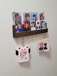 some pictures hanging on a wall with two keychains attached to the hooks