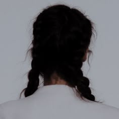 the back of a woman's head, with her hair in a bun and wearing a white shirt