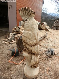 a bird statue sitting on top of a wooden stump