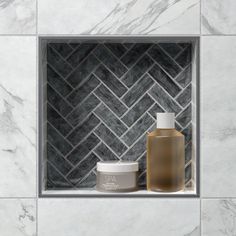 a white and grey bathroom with marble tiles on the wall, two jars for body care