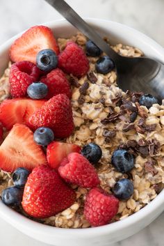 a bowl filled with oatmeal topped with strawberries and blueberries