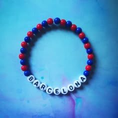 a red, white and blue beaded bracelet with the word barcelona written on it