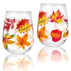 two wine glasses with autumn leaves painted on the glass and one is filled with water