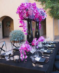 the table is set with black and purple flowers