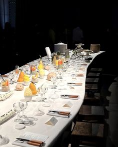 a long table is set with glasses, plates and utensils