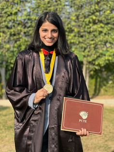 a woman wearing a graduation gown and holding a plaque